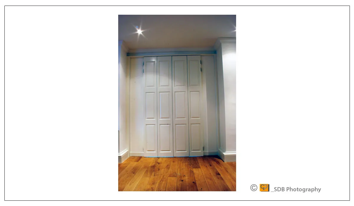  Bi-folding dooers in off white made from English oak showing the field and raised shutter doors shut